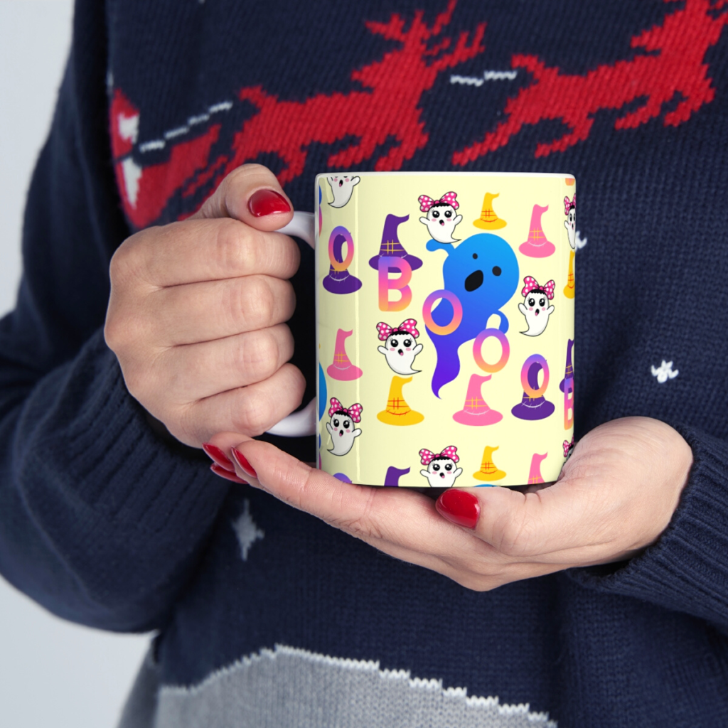 Colorful Boo coffee mug with cute ghost and witch hat pattern held in hands