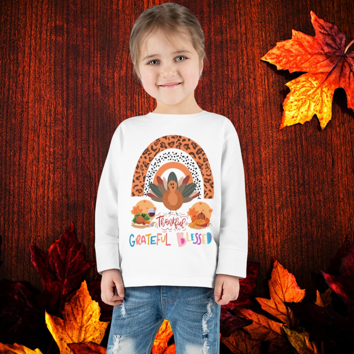 Turkey and leopard rainbow toddler Thanksgiving t-shirt worn by a child model, front view with playful design visible by One Stop Soul