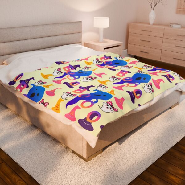 Colorful Boo plush blanket 60x80 with cute ghost and witch hat pattern spread across a modern bed